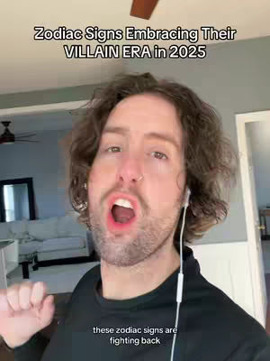 A man with brown hair and a beard is in front of a camera, potentially recording a video. The background shows a domestic interior. Black text overlays at the top and bottom. The man is wearing a black shirt and white earbuds. He has his mouth open. The man's facial expression is animated, suggesting talking or reacting. The background shows a domestic interior, with a white couch and a mirror. Lighting is bright.