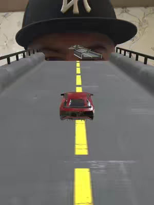 The image is a playful composite. The bottom portion features a red toy car centered on a grey road with a yellow dividing line. Above, the perspective shifts to show the eyes and the lower part of the face of a person wearing a black baseball cap. The person's eyes are looking down towards the car. On top of the road, a separate miniature car also appears to look forward.