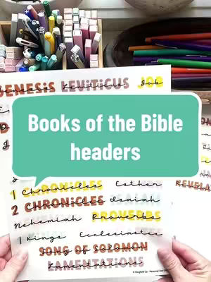 The cover image shows a selection of colorful pens and highlighters in the background. In the foreground, a person holds a sheet of paper with the words "Books of the Bible headers" in a teal speech bubble, with book names written below.