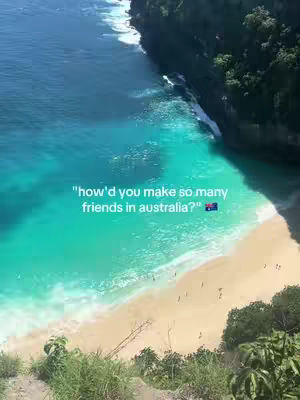 Aerial view of a turquoise ocean meeting a sandy beach, with lush green cliffs to the side and text overlaid on the water.
