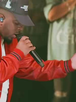 Cover image shows a man in a red jacket singing into a microphone. He's wearing a cap and a small earpiece. The background is out of focus with a person in a green shirt visible, suggesting a live performance setting.