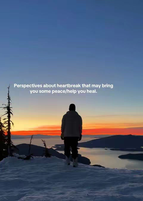 A person stands on a snowy mountain peak, facing away from the viewer. The background shows a colorful sunset with orange and yellow hues over a body of water and distant mountains. Text overlayed at the top reads, 'Perspectives about heartbreak that may bring you some peace/help you heal.'