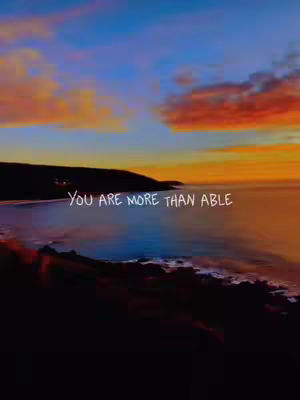 A vertical image showcasing a sunset over the ocean with the phrase, "YOU ARE MORE THAN ABLE" overlaid in white text. The sky transitions from blue to orange and red, and the ocean reflects these colors. A dark landmass appears along the bottom edge.
