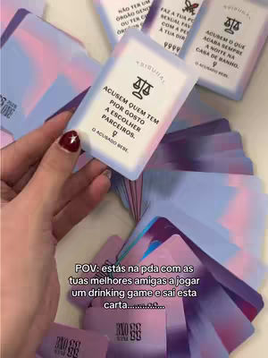 A hand holding a card with text and a scale icon, surrounded by a blurred background of similar cards. The card's text is in Portuguese. The hand has painted nails.
