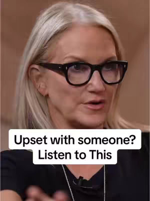 A woman with blonde hair and glasses looks directly into the camera, with text overlaying her image.
