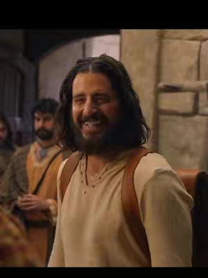 The cover image features a smiling man with a beard in a beige tunic, wearing a brown backpack, likely portraying Jesus. Two other men are visible in the background, and the scene looks to be outdoors. The overall setting suggests a historical or biblical context, with a warm color palette.
