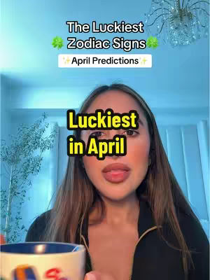 A woman with long brown hair and a black top appears in front of a light blue background. The overlay text says "The Luckiest Zodiac Signs" and "April Predictions". A mug is visible in the bottom left corner of the frame. The text "Luckiest in April" appears as an overlay over the face.