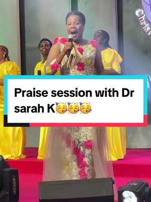 The image shows a woman holding a microphone and singing, with other women in the background. The text overlay reads 'Praise session with Dr sarah K' on a light blue background.