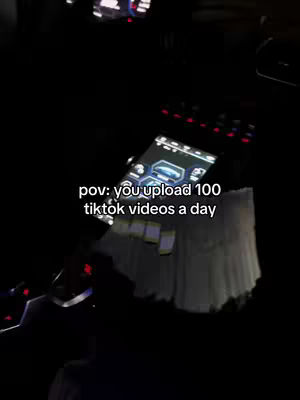A dimly lit interior shot of a car, focusing on the dashboard with a screen displaying various data and a large stack of cash. Text overlayed in the image, at the bottom, reads: 'pov: you upload 100 tiktok videos a day'. 