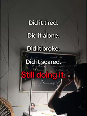 A dimly lit room features a person sitting at a desk with a chalkboard behind them. The chalkboard has some writing on it, likely related to medicine. The text overlay on the image is a motivational message.