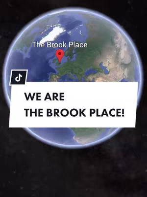 The cover image displays a stylized graphic of the Earth, overlaid with text and a location marker. The Earth graphic is a globe, showing landmasses in shades of green and brown against a blue ocean and a dark space background. Text at the top reads "The Brook Place", with a red location pin indicating a spot in Europe. The lower half features a white rectangular box containing bold, black text: "WE ARE THE BROOK PLACE!"