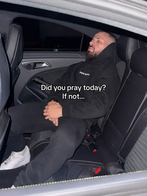 A man in a black hoodie and pants sits in the back seat of a car. Overlay text asks if he prayed today. The car interior is dark, with black leather seats. The overall composition is moody, and the lighting is dim.