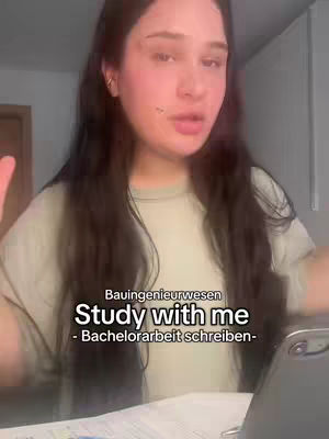 A young woman with long dark hair is in the image, giving a vlog-style, with a neutral background The main visual elements are the woman and overlaid text. The woman is speaking or singing.
