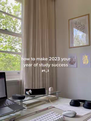 The cover image shows a well-lit study space with a window on the left letting in natural light. The window has beige curtains. A desk is in the foreground with a laptop, books, headphones, a mouse, and a keyboard. The text overlayed on the image reads: "how to make 2023 your year of study success / pt_1". On the right side, there's framed artwork on the wall.
