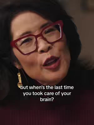 A woman with black hair and red glasses in a close up shot.