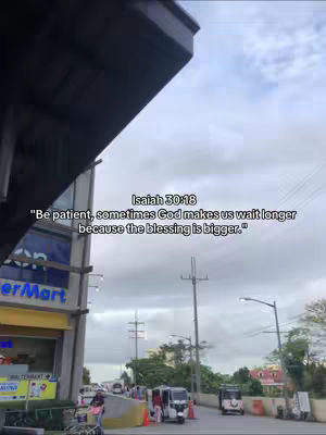 A photo taken from a low angle, looking up at a building and the sky. Text is overlaid on the image, with a quote from Isaiah 30:18. The background includes a street with vehicles and utility poles.