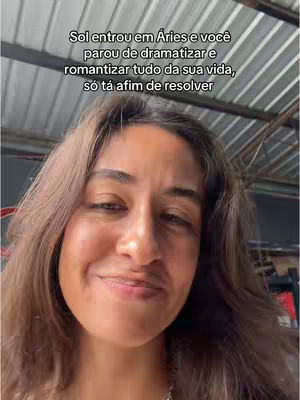 A selfie-style shot features a woman with long brown hair against a lightly blurred indoor background with a ceiling. She is looking at the camera with a slight smile. Text on the image reads, "Sol entrou em Aries e você parou de dramatizar e romantizar tudo da sua vida, só tá afim de resolver".