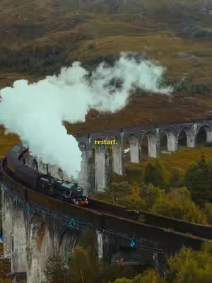 An overhead shot captures a scenic view of a train traveling along a curved bridge. The bridge is an impressive stone structure with multiple arches, set against a backdrop of rolling hills and a cloudy sky. Smoke billows dramatically from the train, adding a sense of movement and atmosphere to the scene. The text overlay 'restart' appears in a yellow font.