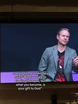 A man in a gray blazer and black t-shirt stands on stage. The quote "It really hit me when they said: 'What you are, is God's gift to you, but what you become, is your gift to God'" appears as an overlay.