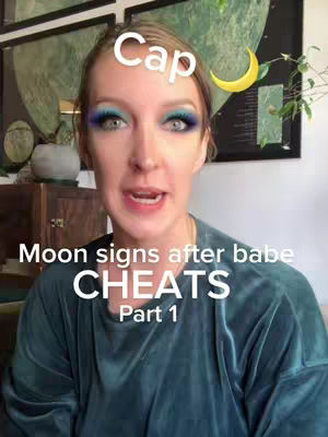 A well-lit selfie featuring a woman with light skin and visible makeup. Light blue eyeshadow is present, her full lips are subtly parted, and she has a serene expression. The background includes glimpses of framed artwork, decorative objects, and a wooden cabinet, suggesting an indoor setting. Text overlays featuring the word "Cap", a crescent moon, and text related to moon signs and cheating are interspersed throughout the cover image. The composition is balanced, with the woman centrally positioned, and the overall effect is engaging.