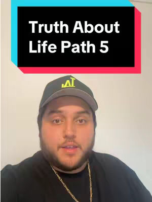A man wearing a black cap and shirt is centered in the frame, looking directly at the camera. Above him is a text overlay in a rectangular shape, which reads "Truth About Life Path 5". The background is a solid pale color, and a gold chain is visible around the man's neck.