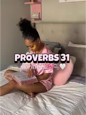 A woman is sitting on a bed with a book in her lap, with a decorative pink element on her pillow. The overhead text overlay on the image reads, "PROVERBS 31 mornings".