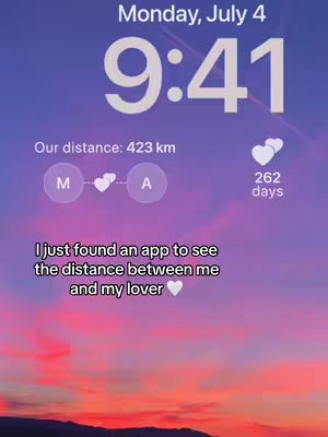 The image is a phone lock screen displaying the date, time, and distance between two people. The top part of the screen shows the date, 'Monday, July 4', and the time '9:41' in large, white font. Below this, there are text lines indicating the distance, 'Our distance: 423 km'. Beneath that, there are two circular icons with the letters 'M' and 'A' inside, connected by a heart icon. A count of '262 days' appears to the right, in small, white text. Near the bottom a text overlay says: 'I just found an app to see the distance between me and my lover 🤍'. The background is a vibrant gradient of pink, and purple hues, suggesting a sunset or sunrise over tree tops.