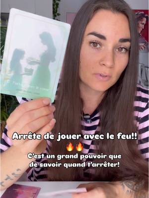 A woman with long brown hair is centered in the frame, holding up a card from a tarot deck. The card depicts two silhouettes of a woman and a child. The woman is wearing a pink and black striped shirt. The background features text overlay with a call to action.