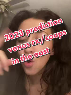 A selfie-style video cover features a person with dark hair against a dimly lit background. Large, bold text overlays the image, with a red and white color scheme, describing "2023 prediction venus rx/coups in the east". The person is looking at the camera, and the composition is focused on the upper body.