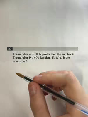A close-up shot shows a hand holding a pen resting on a sheet of paper with a math problem printed on it. The problem involves a percentage calculation, which is the main focus, with parts of equations visible on the paper. The background has a neutral tone, making the text stand out along with the pen and hand which are sharp and focused.