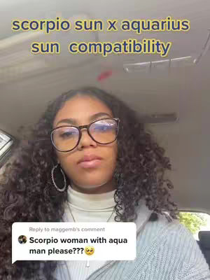A young woman with curly hair and glasses is seated in a car. She is looking forward with a composed expression. Above her, yellow text reads, "scorpio sun x aquarius sun compatibility." A comment bubble at the bottom left of the image invites her to give an analysis on a "Scorpio woman with aqua man."