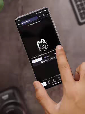 The image shows a smartphone held at an angle, displaying a website within a webpage. The foreground is a hand interacting with the phone's screen.