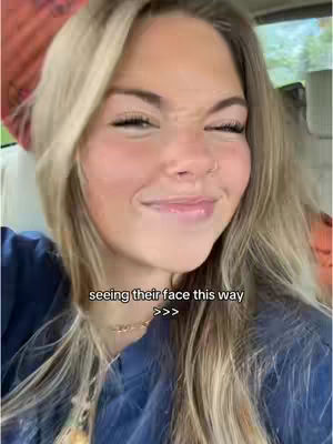 A selfie of a woman in front of a blurred background. She has blonde hair and is wearing a dark blue shirt. Text overlayed says, "seeing their face this way >>>".