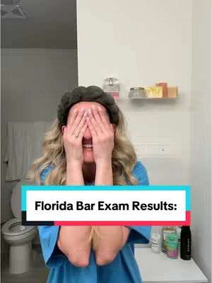 A woman stands in a bathroom, covering her eyes with both hands. She wears a blue top, and a headband. The background includes a mirror, toiletries, and a toilet. A text overlay reads "Florida Bar Exam Results:" in a colorful banner across the bottom of the image.