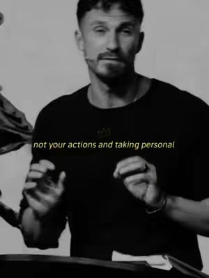 A grayscale image featuring a man with short, styled hair and a slight mustache, centered in the frame. He's wearing a black t-shirt, and the image has text overlaid in yellow at the bottom: 'not your actions and taking personal.' The man is gesturing with his hands as if speaking, and his expression conveys thoughtfulness. The background has a soft, out-of-focus quality. The overall composition is simple, with a focus on the subject.