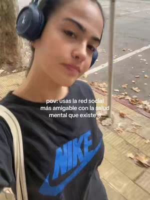 A young woman wearing headphones and a Nike shirt stands outside, with text overlaid on the image. The background shows a street scene with trees and a sidewalk.