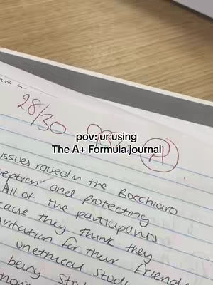 The cover image shows a close-up of a piece of paper with handwritten notes. The top-left corner has a score of 28/30. The overlaid text reads, "pov: ur using The A+ Formula journal." A circled 'A' is also present. The background is a wooden surface.