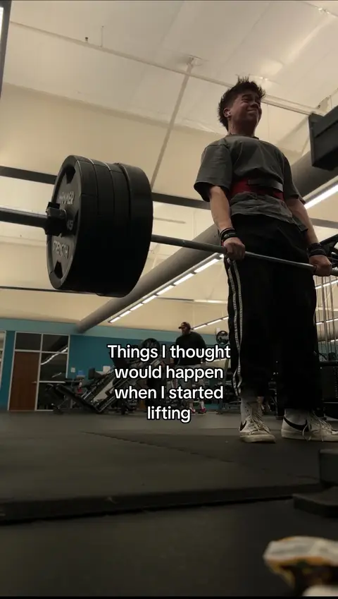 A young man is lifting weights in a gym. He is wearing a black t-shirt, black shorts, a weightlifting belt, and white sneakers. Text is overlaid on the image.
