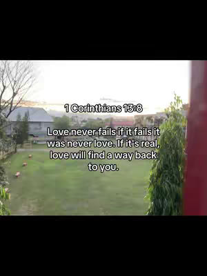 The image shows a scenic outdoor view with text overlaid. The background is a grassy field and trees, with glimpses of buildings, under a bright sky. The text quotes a Bible verse about love.