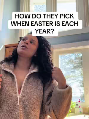A woman with dark, curly hair stands indoors, lit by daylight from a large window. She wears a textured, neutral-toned fleece sweater and looks upwards with a questioning expression. A text overlay asks a question about when Easter is each year.