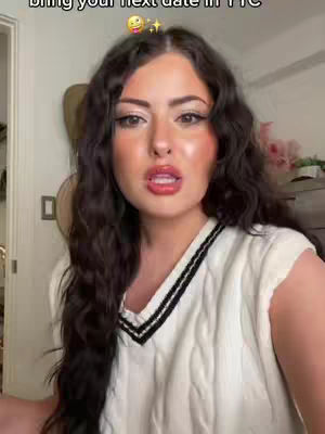 A woman with long, dark curly hair and full makeup is looking directly at the camera, her mouth slightly open, against a blurred background. Text overlays her image, with emoji enhancements.