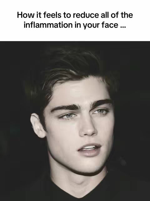 The image features a close-up shot of a young man's face against a dark background. He has light skin, styled dark hair, and prominent eyebrows. The lighting highlights the shape of his face, with a focus on his eyes, nose, and lips. The overall composition is simple, drawing attention to the man's facial features.