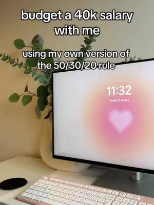 A cover image showing a computer screen with the text 'budget a 40k salary with me' overlaid on top, along with a plant to the left of the screen, and a keyboard in the foreground. The screen displays a heart-shaped design with the time 11:32.