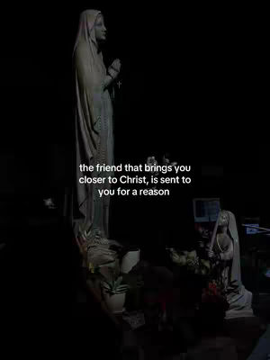 The cover image presents a dimly lit scene with a statue in the foreground. The statue is a tall, slender figure dressed in draped clothing, giving the impression of a religious or spiritual icon. The statue is made of stone, with a muted color palette. At the bottom a smaller statue of a similar figure alongside flowers.