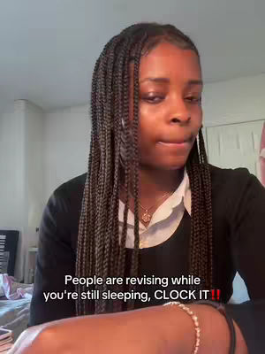 A young woman with long, braided black hair and a white collared shirt under a black sweater is looking at the camera. The background is a simple room with a plain wall. Text overlayed on the image says an inspirational message.