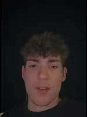The cover image shows a close-up of a young man. He has short, curly brown hair and fair skin. He is wearing a dark-colored shirt. The background is a solid black.