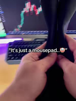 The cover image shows a person's hands holding a black object in front of them, while a computer screen with a stock chart is visible in the background. Text overlayed on the image reads, "It's just a mousepad.." followed by a clown face emoji.