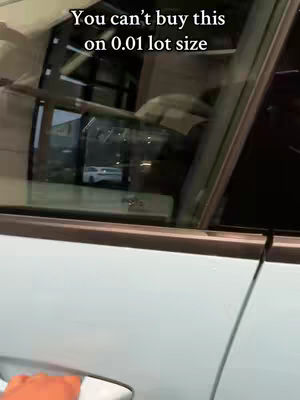 The cover image shows a view from inside a car. The shot is framed through the car's window and door, with the door handle visible in the lower left corner. The outside view reveals a glimpse of what appears to be a building and another car further in the distance. The dominant color is a light blue, consistent with the car door.