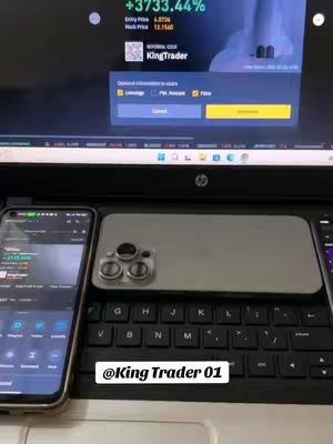 The image shows a laptop, two smartphones, and an iPhone on a desk or table. The laptop screen displays a trading interface, and the smartphones show market data. The overall composition seems to be a workspace oriented towards crypto trading.