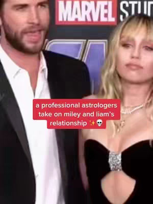The image shows a couple in front of a banner reading "MARVEL STUDIOS". Text overlaid in a red box states, "a professional astrologers take on miley and liam's relationship." The woman is blonde and wearing a black dress with a diamond embellishment. The man is wearing a black suit with a white shirt.